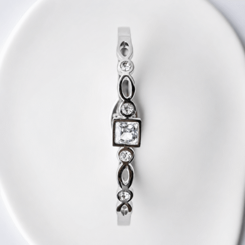 Silver Princess Cut Geometric Bangle on a plaster background