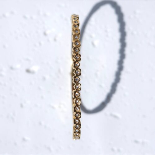 Gold Scalloped Heart Eternity Bangle on plaster background